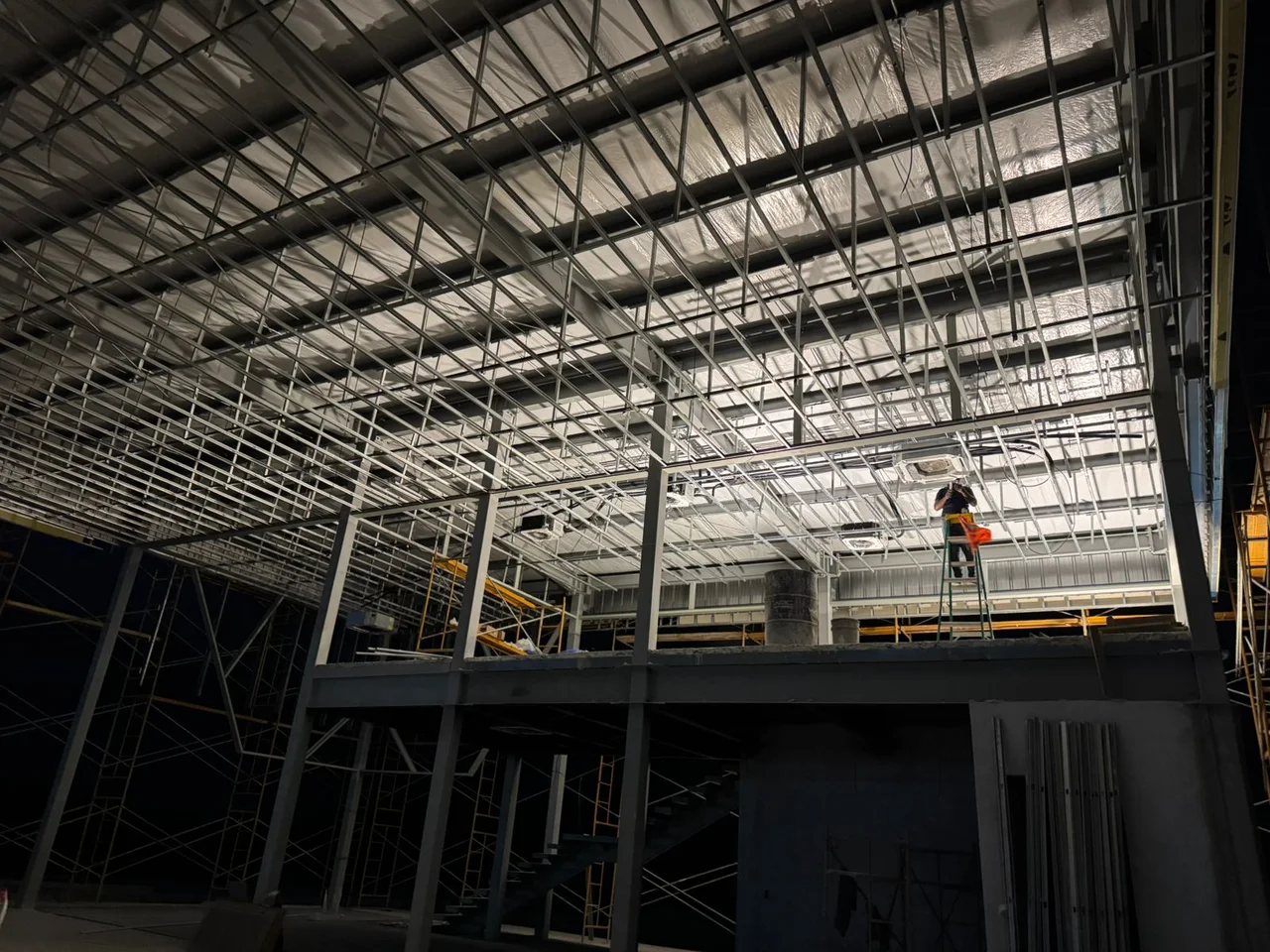 Technician on a ladder carrying out climate-control installation work indoors