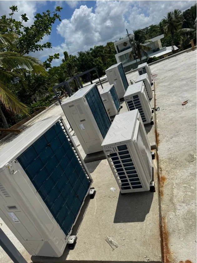 Several outdoor climate-control units on a rooftop surrounded by greenery