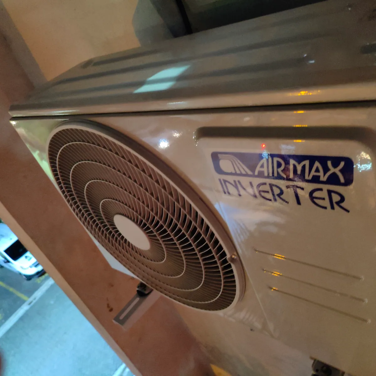 Outdoor air-conditioning unit mounted on a wall beside a window