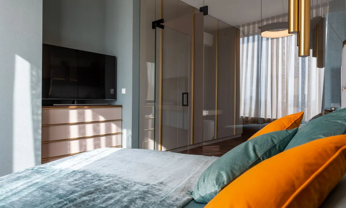 Dormitorio con almohadas de colores y un mueble de televisión